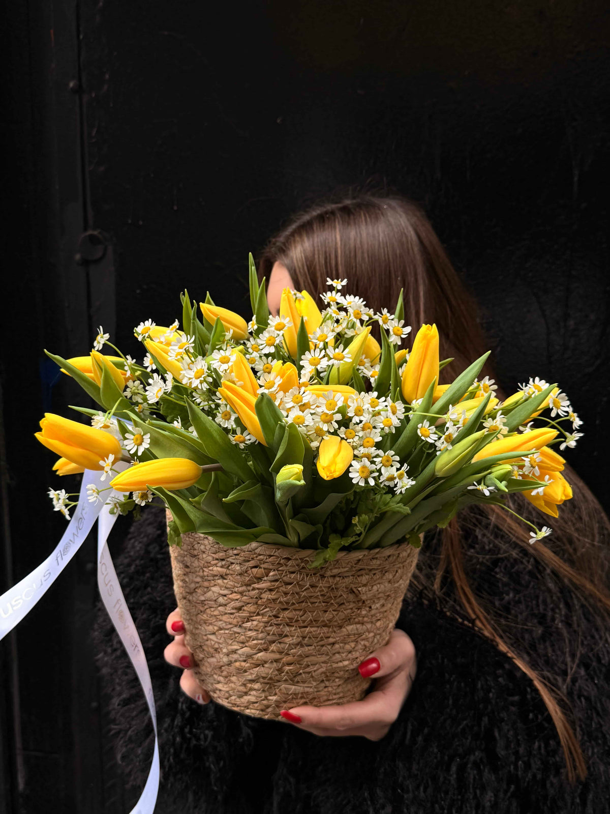 Basket with yellow tulips and white daisies arranged in a woven container