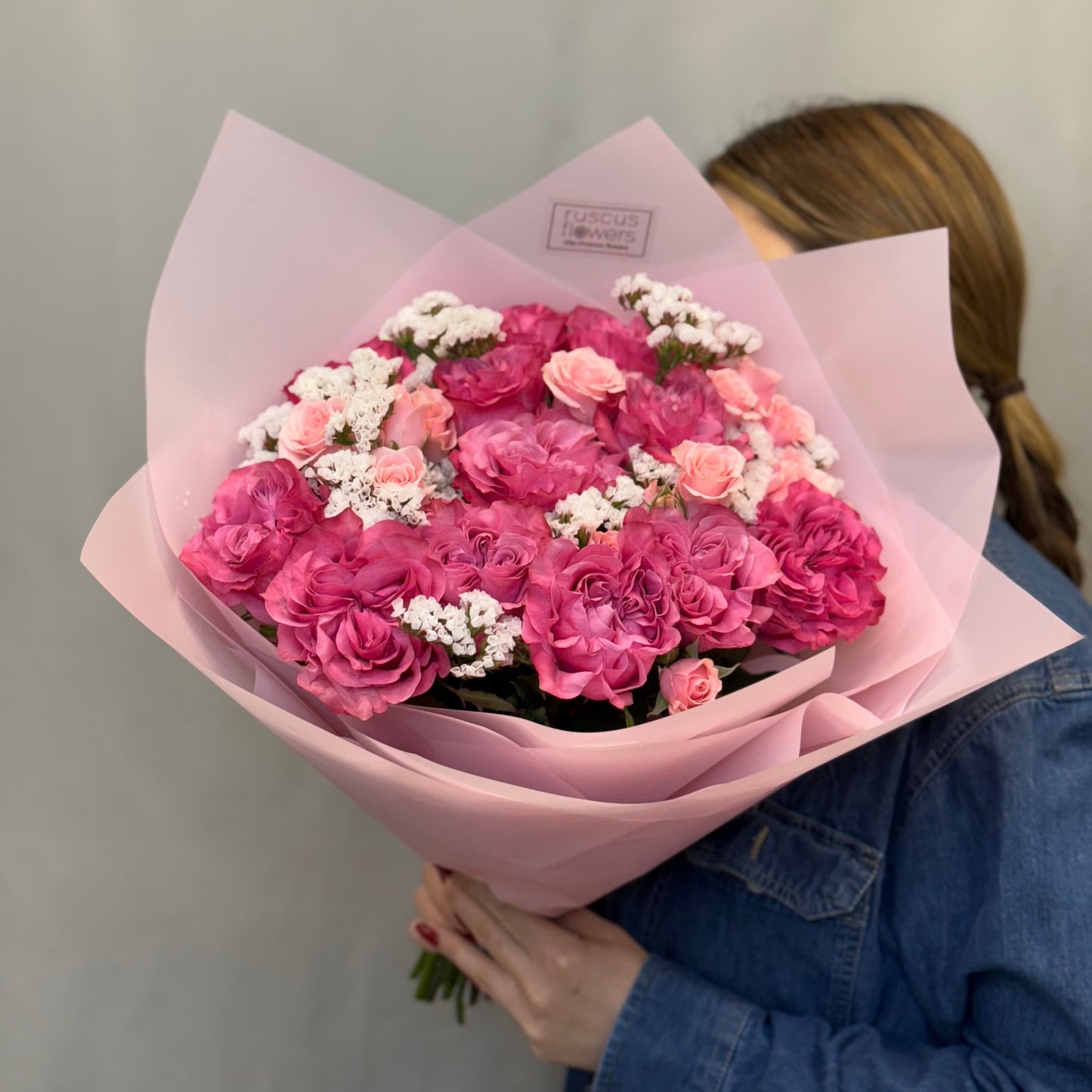 Deep pink roses with purple statice and greenery in bouquet