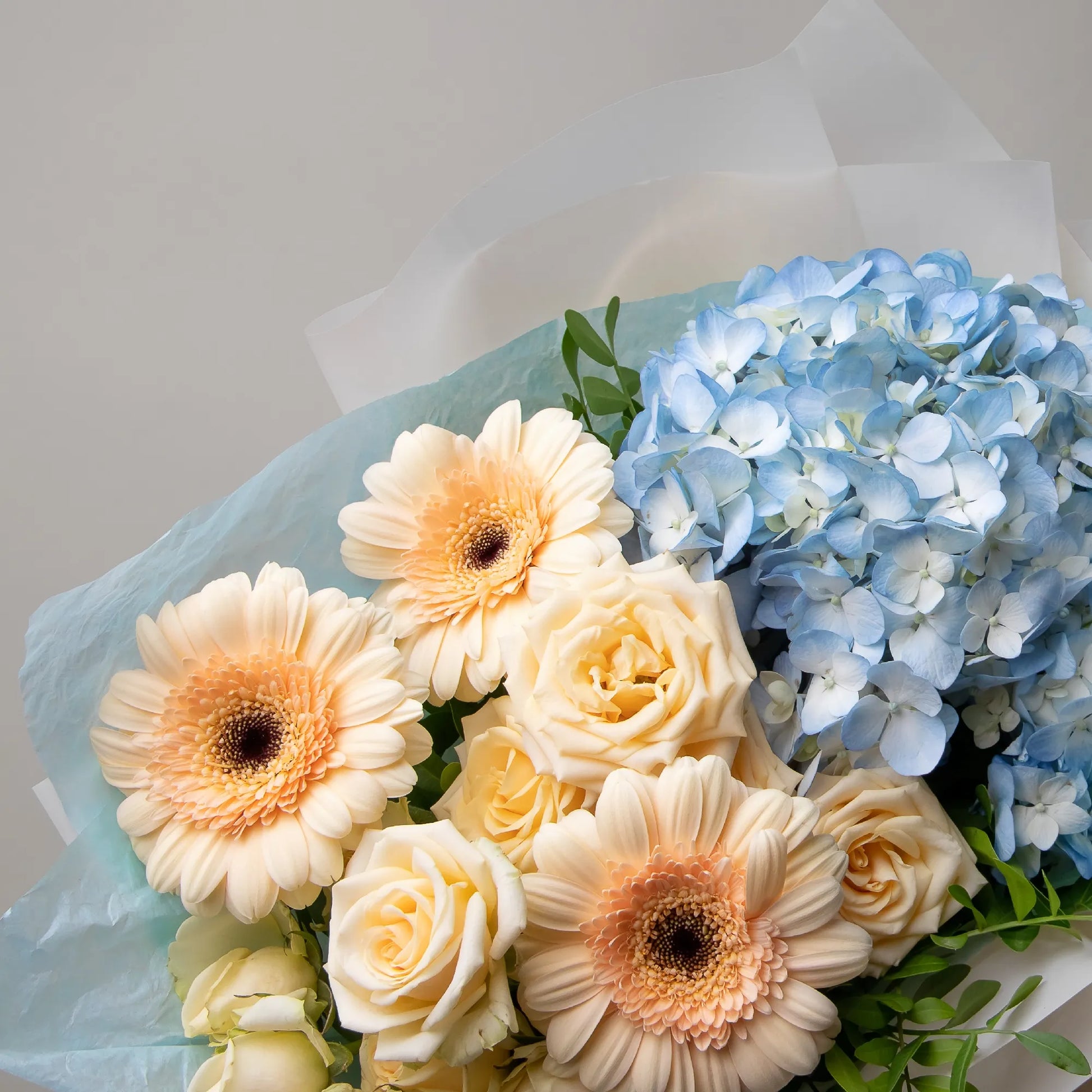 Close-up of hydrangea, gerbera, and spray roses in soft bouquet