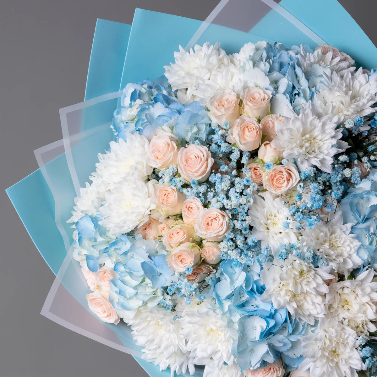 Close-up of blue hydrangeas, spray roses, and gypsophila in bouquet