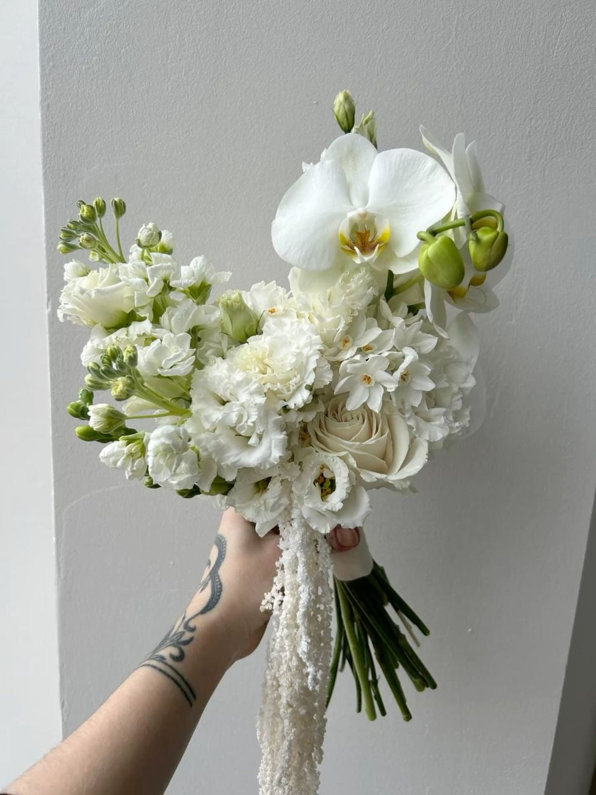 White bridal bouquet with orchids, roses, lisianthus, and stock with cascading accents.