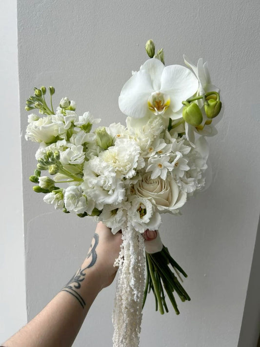 White bridal bouquet with orchids, roses, lisianthus, and stock with cascading accents.