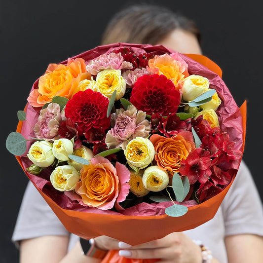 Bouquet of colorful flowers held by a person against a dark background