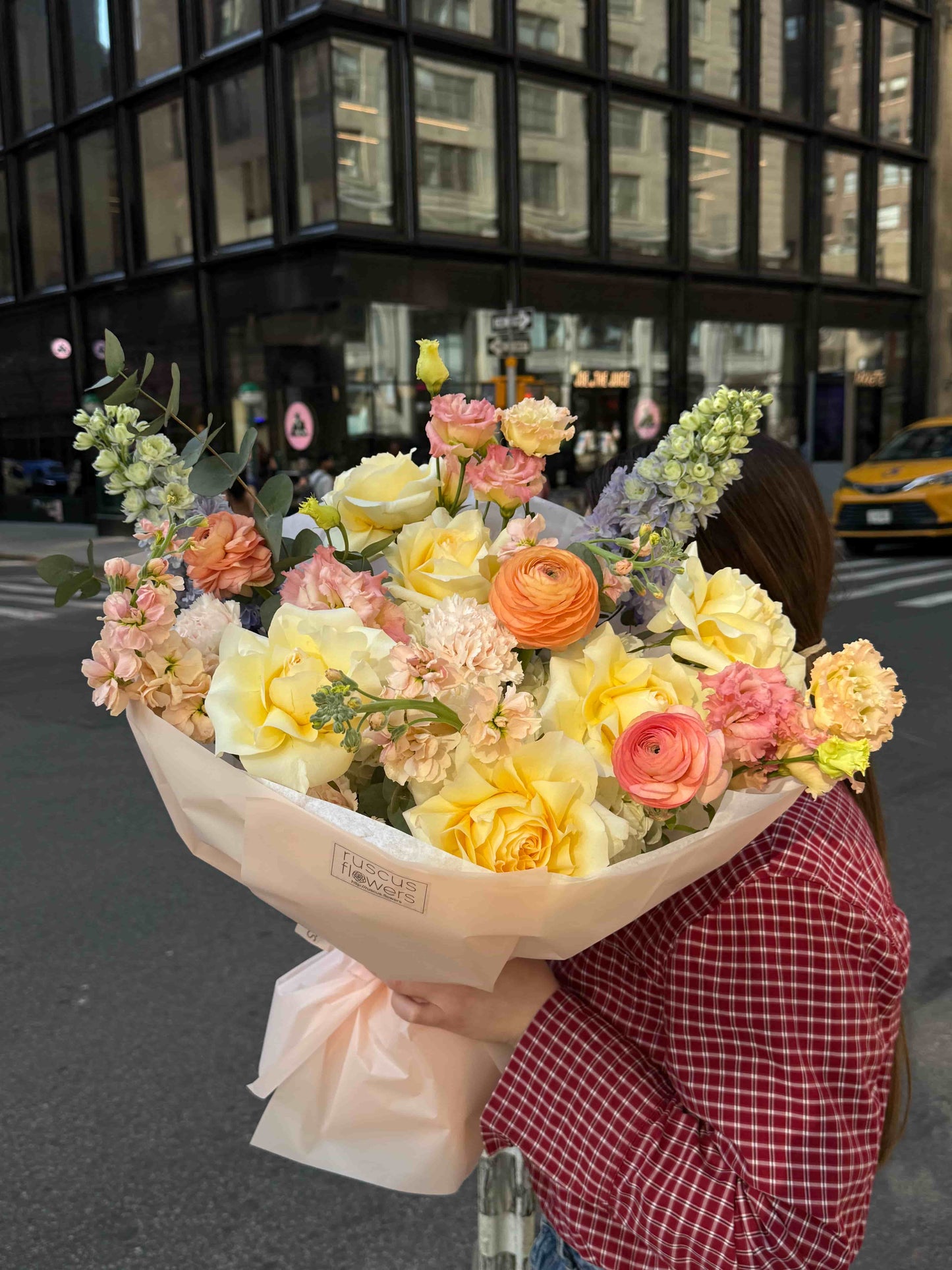 Mixed bouquet with delphinium, roses and ranunculus in soft pastel wrapping
