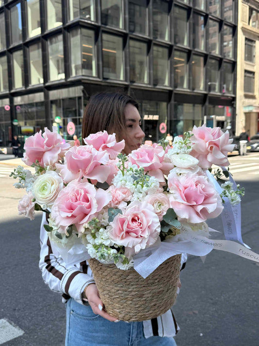 Basket with French roses, hydrangeas and ranunculus in soft garden style