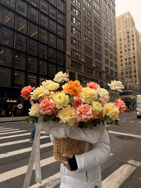 Basket with French roses, hydrangeas and ranunculus in pastel tones