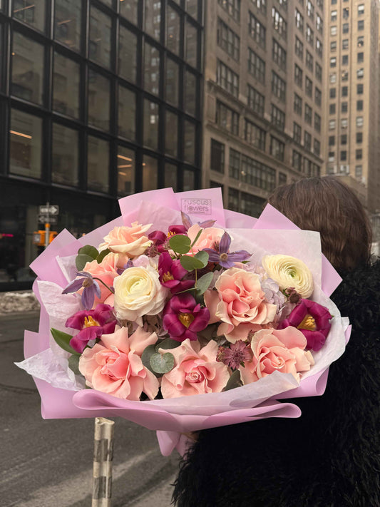 Luxury bouquet with French roses, ranunculus and clematis in pastel wrapping