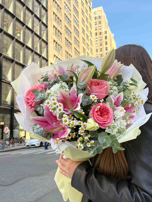 Mixed bouquet with lilies, garden roses and daisies wrapped in soft paper