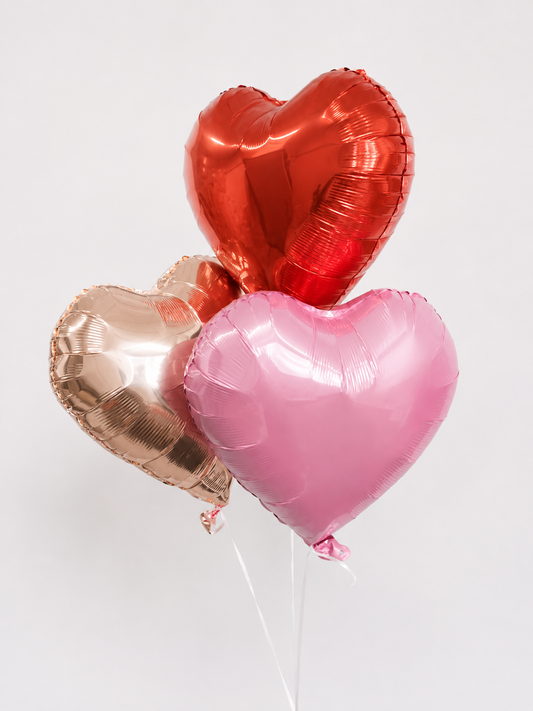 Three heart-shaped foil balloons in red pink and champagne