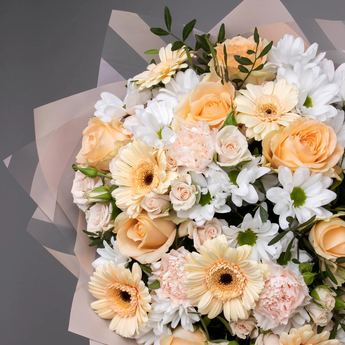 Close-up of peach roses, gerbera, and spray blooms in warm bouquet