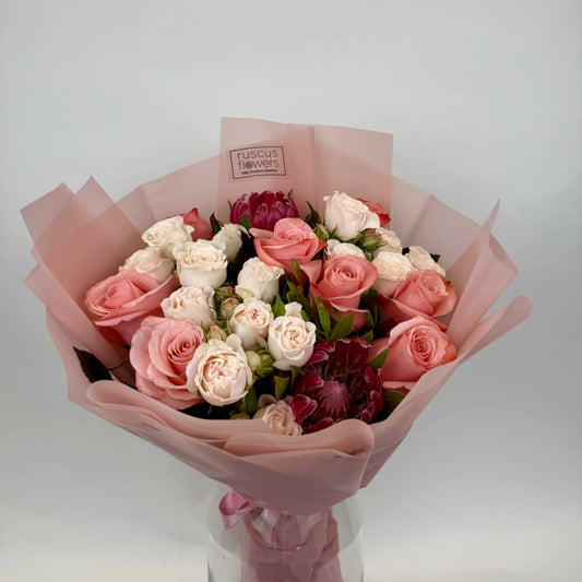 Bouquet with protea, roses, garden spray roses, and pistachio leaves