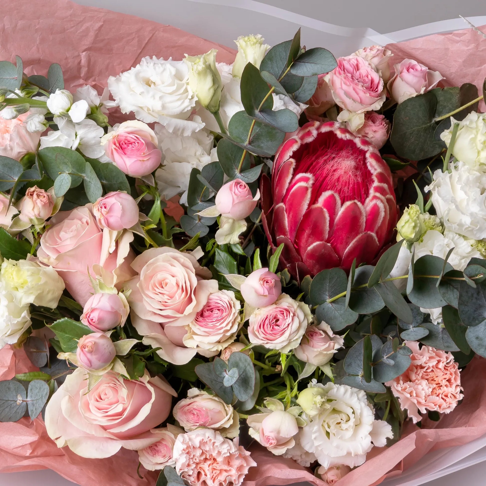 Close-up of protea and roses in soft floral arrangement