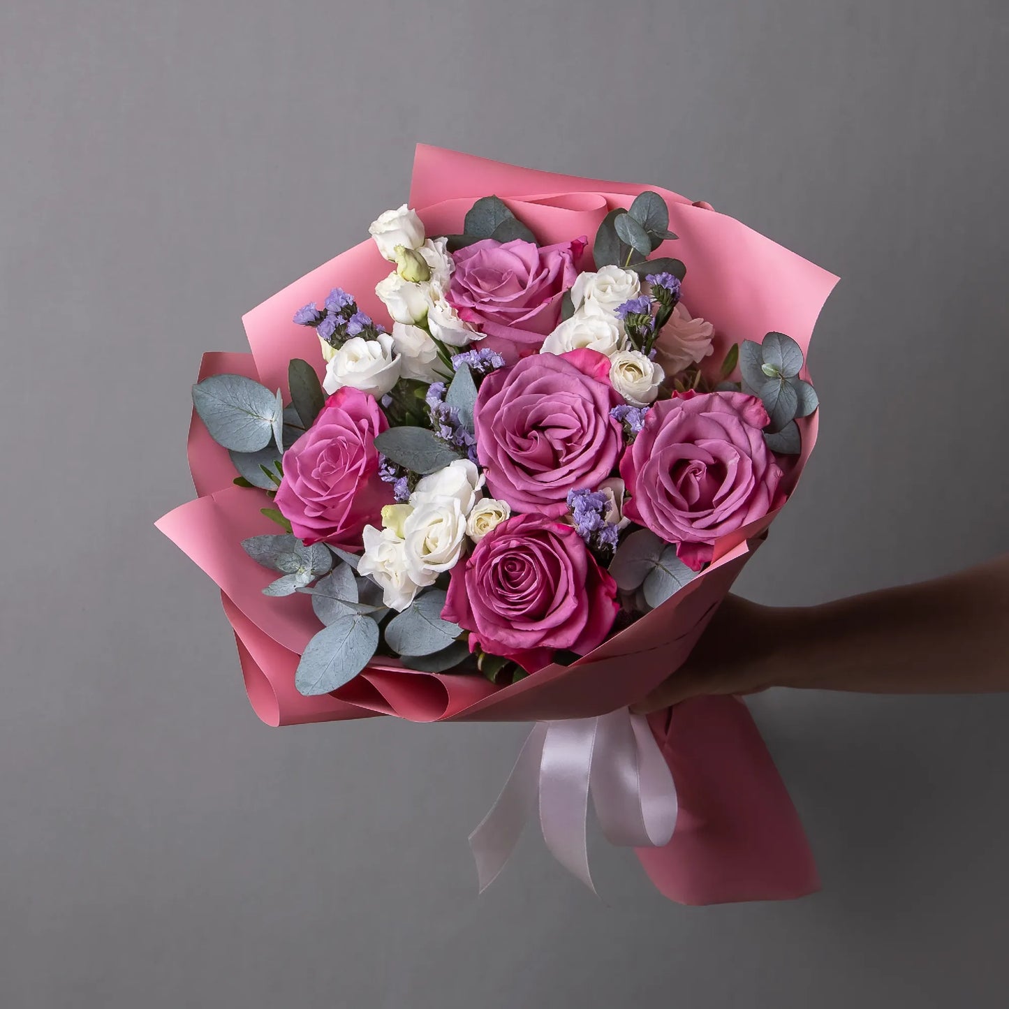Bouquet with purple roses, white lisianthus, and greenery