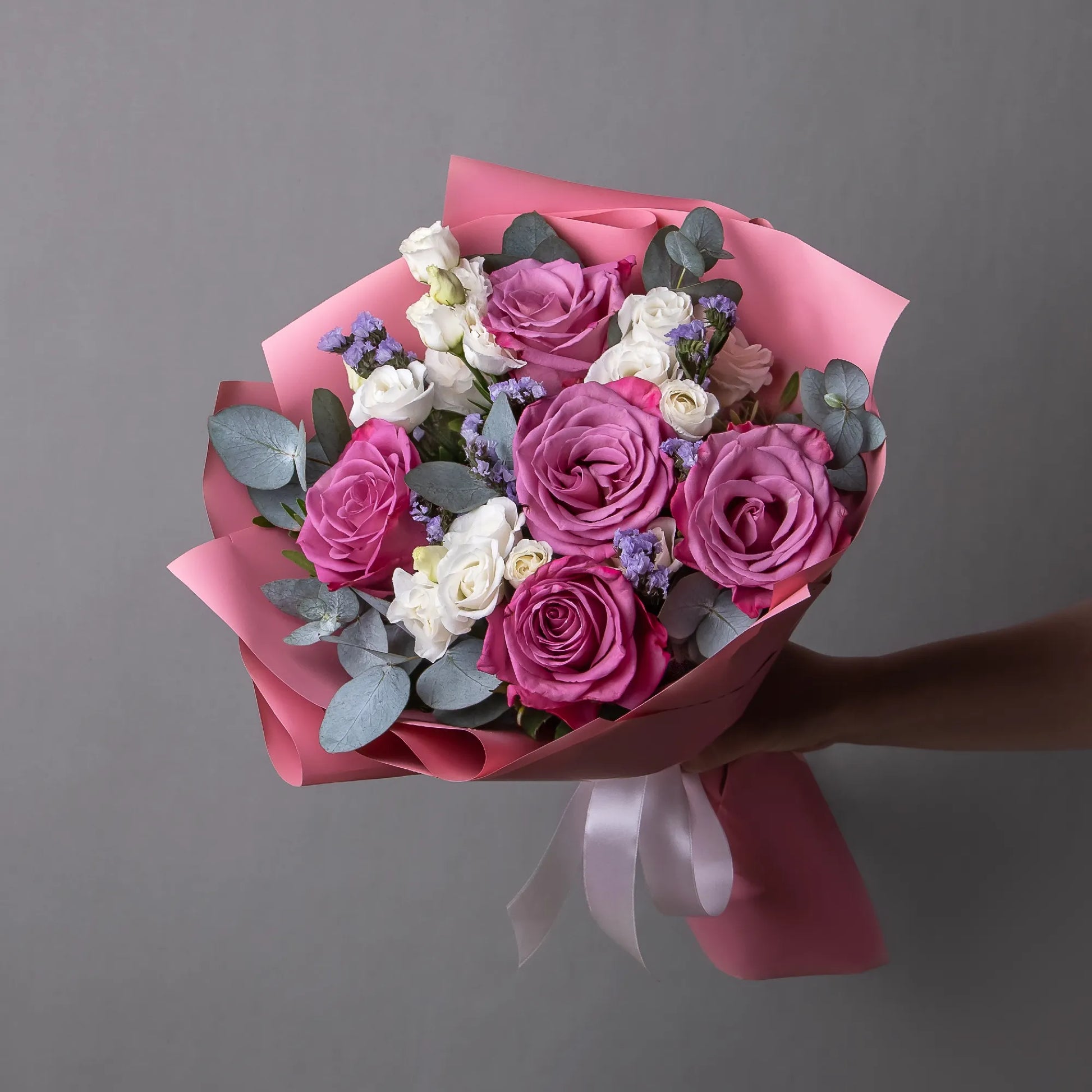 Bouquet with purple roses, white lisianthus, and greenery