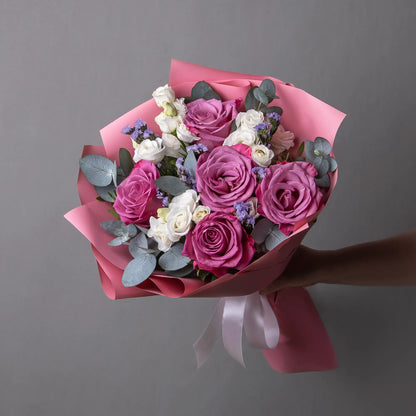 Bouquet with purple roses, white lisianthus, and greenery