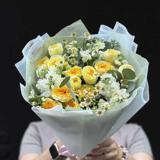 Bouquet of yellow and white flowers held against a black background