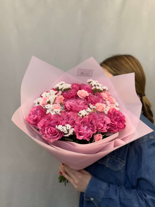 Deep pink roses with purple statice and greenery in bouquet