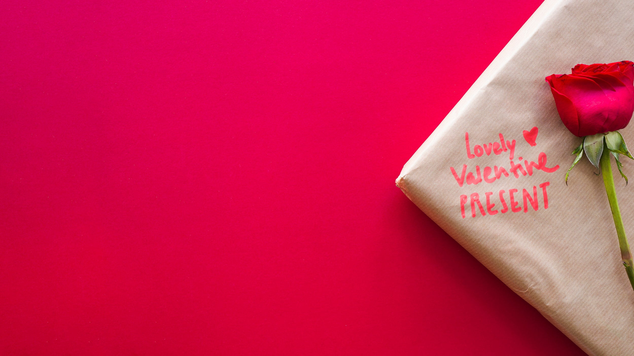 Valentine's Day gift wrapped with red rose on red background