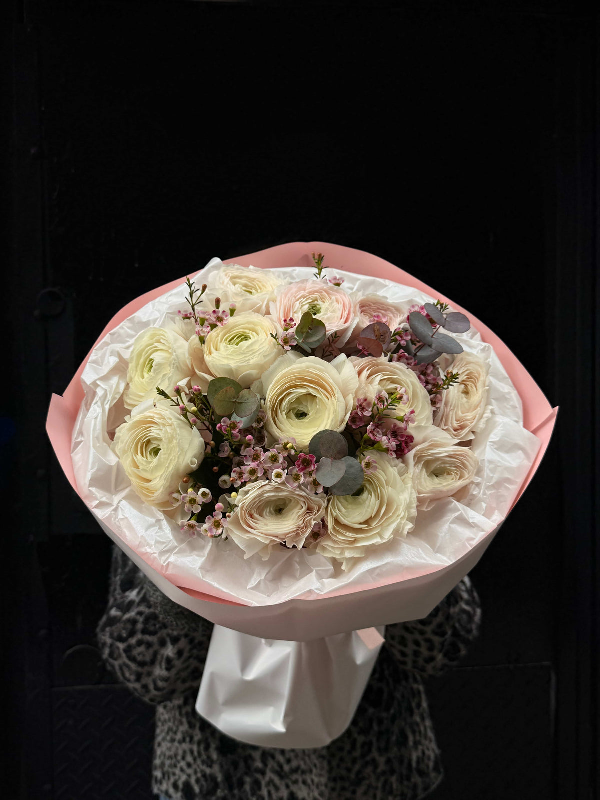 White ranunculus bouquet with waxflower and eucalyptus in pastel wrapping