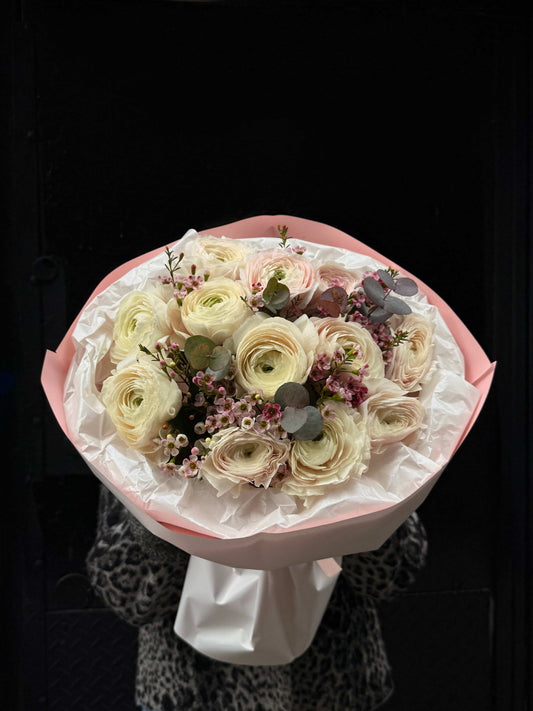 White ranunculus bouquet with waxflower and eucalyptus in pastel wrapping
